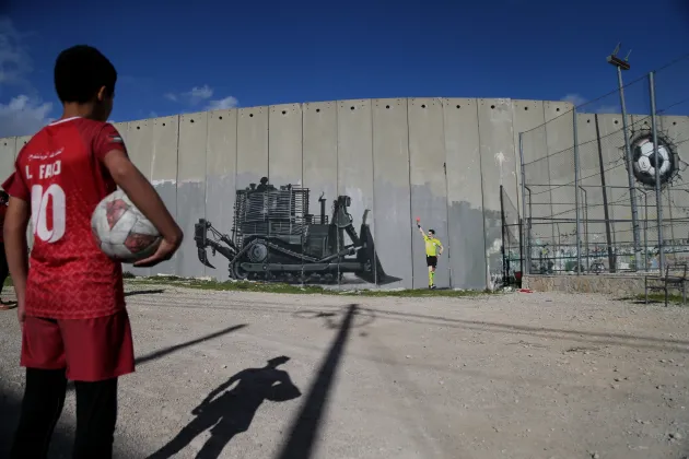 Boy holds football and looks at graffiti 