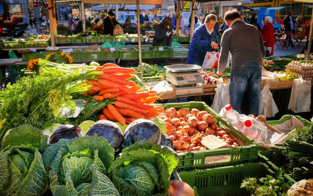 A farmers market where all sorts of vegetables can be seen including carrots, onions, cabbages. 