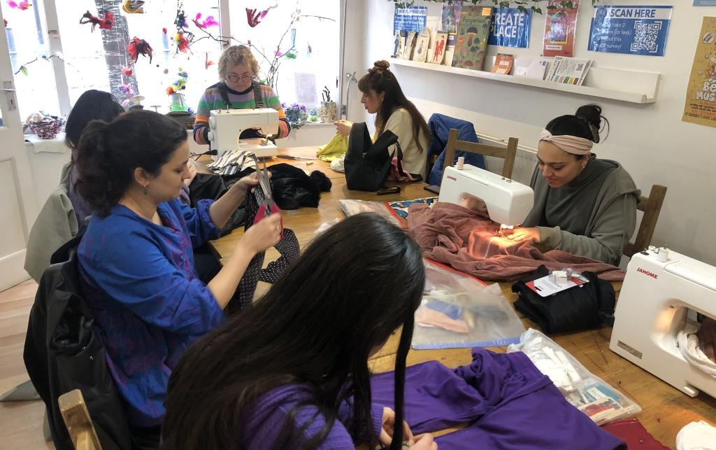 A group of participants taking part in a clothes mending and alteration workshop at East Fashion Therapy, London UK, 2023