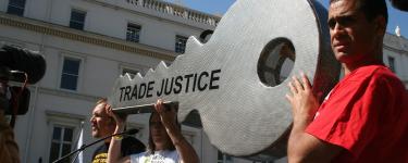 People at the front of a rally hold a giant key engraved with the words 'Trade Justice'. Photo: Trade Justice Movement
