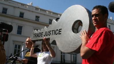 People at the front of a rally hold a giant key engraved with the words 'Trade Justice'. Photo: Trade Justice Movement