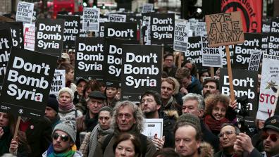 A demonstration in which many people are holding "Don't Bomb Syria" placards, and one placard says "We are many".