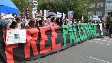 Protesters hold a large batter that reads "Free Palestine!" at a demonstration.