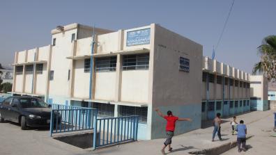 A UNRWA school with children walking by outside. The sign on the front of the building reads: "UNRWA North Amman Area, Department of Education, Baq'A Elem. Boys School no. 3&4. Photo: خليل مزرعاوي, / Addustour, Jordan Press & Publication Co. http://addustour.com/